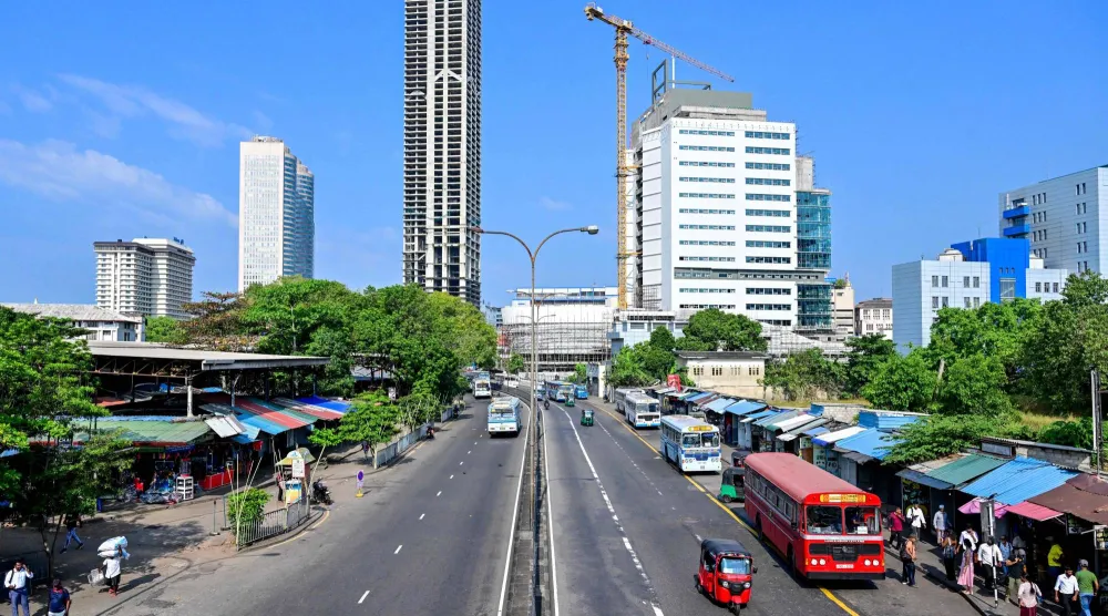 ينتظر الركاب وسائل النقل العام على طول طريق مهجور في كولومبو (أ.ف.ب)