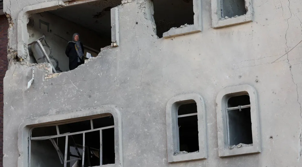 سيدة تقف داخل مبنى تعرض للقصف الإسرائيلي الأميركي في طهران (رويترز)