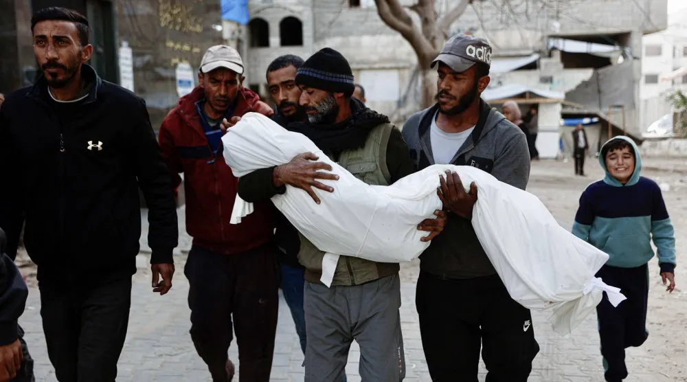 فلسطيني يحمل جثمان أحد أقربائه قتل في غارة جوية إسرائيلية بمدينة غزة (أ.ف.ب)