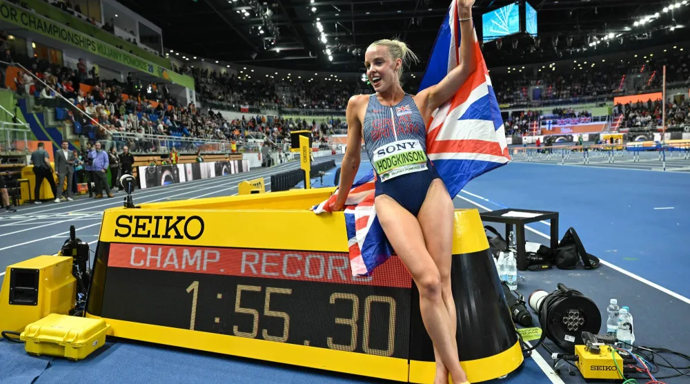 العداءة البريطانية كيلي هودجكينسون تحتفل بلقبها العالمي الأول داخل قاعة (إ.ب.أ)