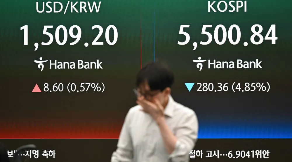 أحد تجار العملات يمر أمام شاشة تعرض مؤشر بورصة كوريا الجنوبية (كوسبي) وسعر صرف الوون الكوري مقابل الدولار الأميركي (أ.ف.ب) 