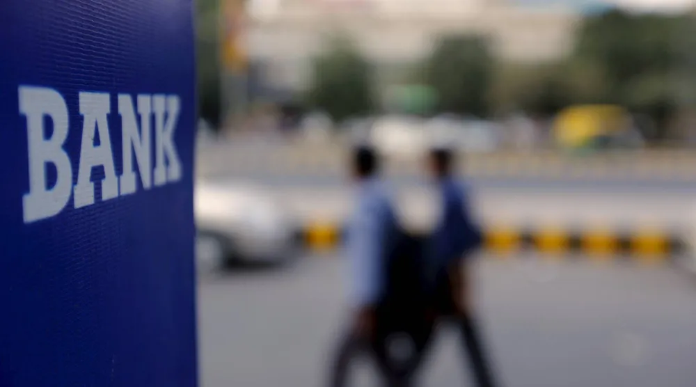 مارّة بجانب لافتة بنك بطريق في نيودلهي (رويترز)