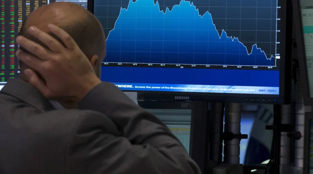 أحد المتخصصين في التداول يراقب شاشة داخل بورصة نيويورك (رويترز)