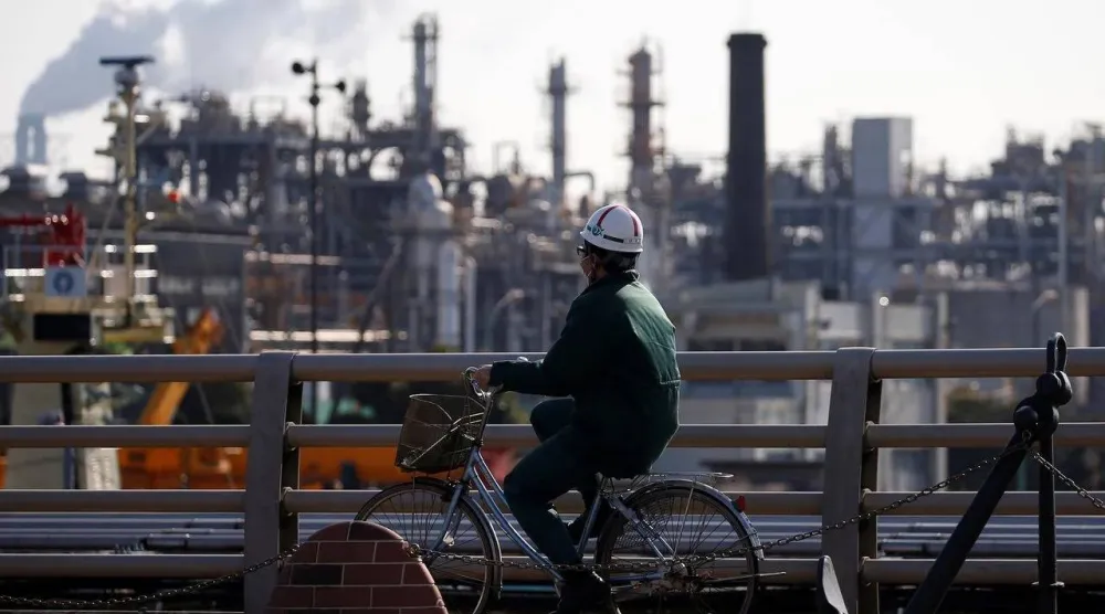 فني يسير بجوار إحدى مصافي النفط اليابانية (رويترز)