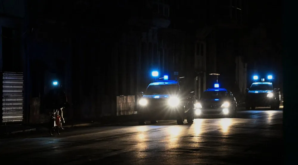 سيارات الشرطة تجوب شارعاً معتماً خلال انقطاع التيار الكهربائي الشامل في هافانا (أ.ف.ب)