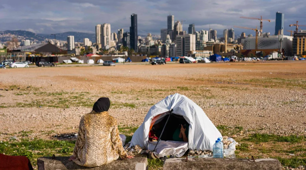 نازحة لبنانية من الضاحية الجنوبية لبيروت قرب خيمتها على واجهة بيروت البحرية (أ.ف.ب)