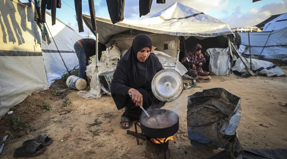 فلسطينية تعد وجبة في مخيم النصيرات للاجئين شمال دير البلح وسط قطاع غزة (أ.ف.ب)