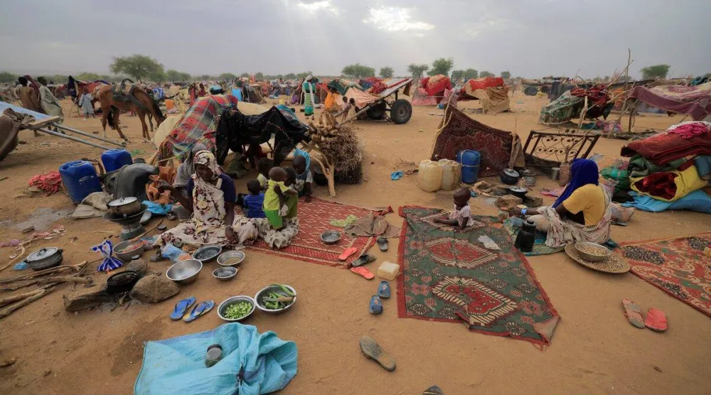 لاجئات سودانيات فررن من العنف في إقليم دارفور السوداني يُحضِّرن وجبة الإفطار بجوار ملاجئهن المؤقتة قرب الحدود بين السودان وتشاد في كوفرون التشادية يوم 11 مايو 2023 (رويترز)