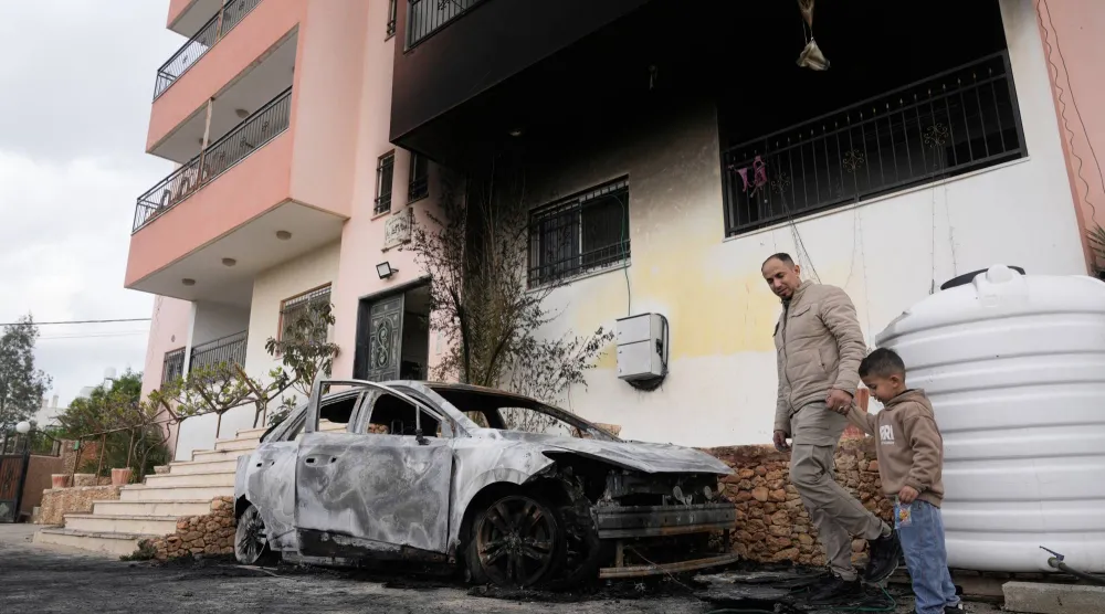 فلسطينيون يتفقدون يوم الاثنين مركبة محترقة في أعقاب هجوم المستوطنين على قرى قرب نابلس بالضفة الغربية (أ.ب)