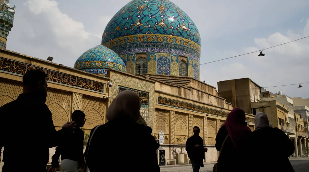 يمر الناس أمام مسجد حيدر خانة في شارع رشيد بوسط مدينة بغداد (أ.ب) 