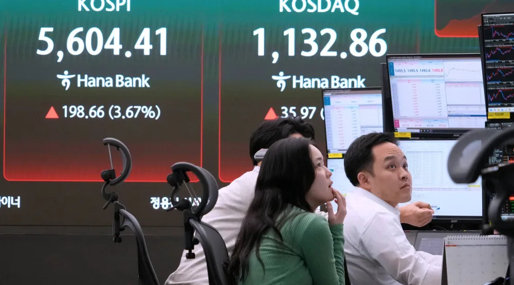 يراقب متداولو العملات شاشات بالقرب من شاشة تعرض مؤشر أسعار الأسهم الكوري المركب (كوسبي) في سيول (أ.ب)