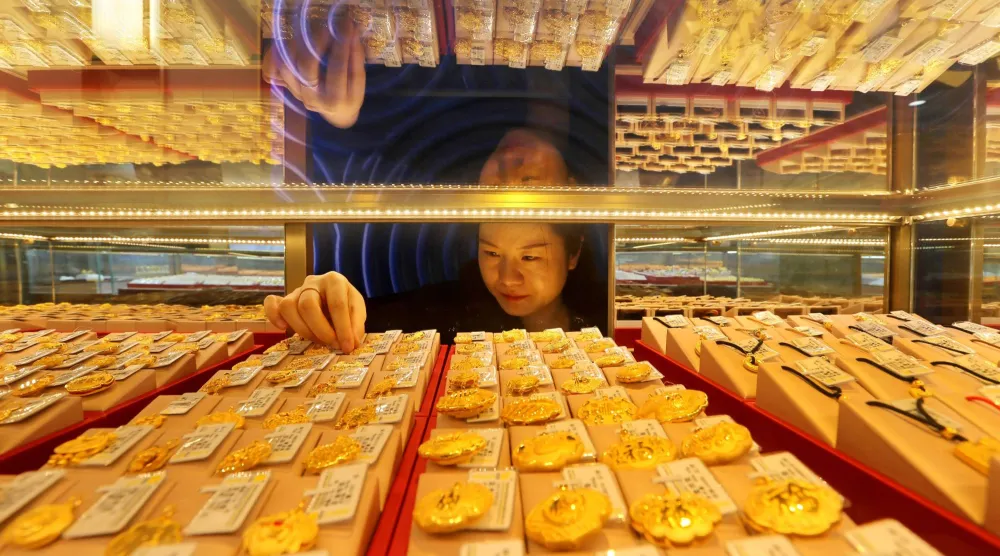 بائعة تقوم بتعديل مجوهرات ذهبية معروضة للبيع في متجر بمدينة ليانيونغانغ في شرق الصين (أ.ف.ب)