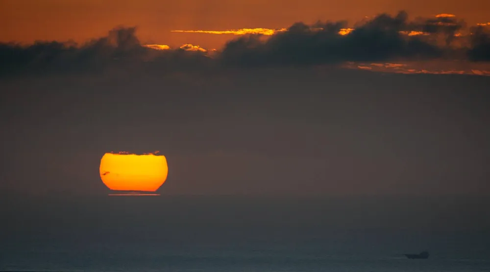 قارب صيد يبحر مع غروب الشمس في الخليج العربي بالإمارات (أ.ب)
