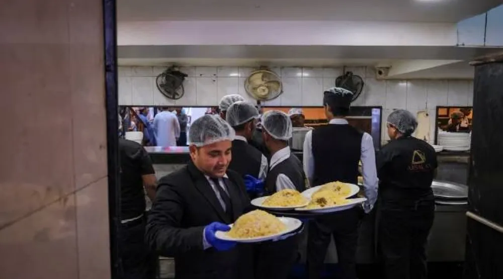 نادل يحمل طبق برياني لتقديمه للزبائن داخل مطعم في كولكاتا بالهند (رويترز)
