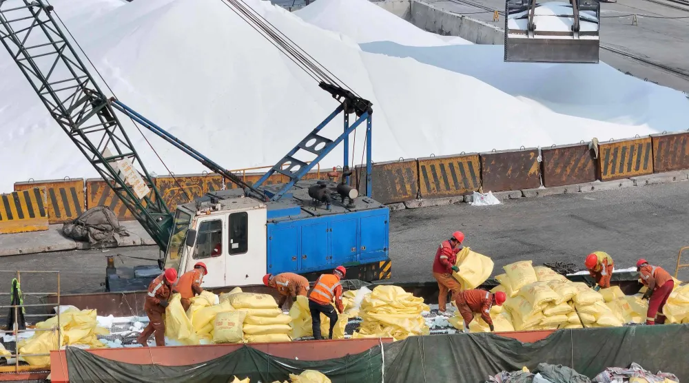 عمال يحمّلون أجولة من السماد في ميناء مدينة يانتاي الصينية (أ.ف.ب)