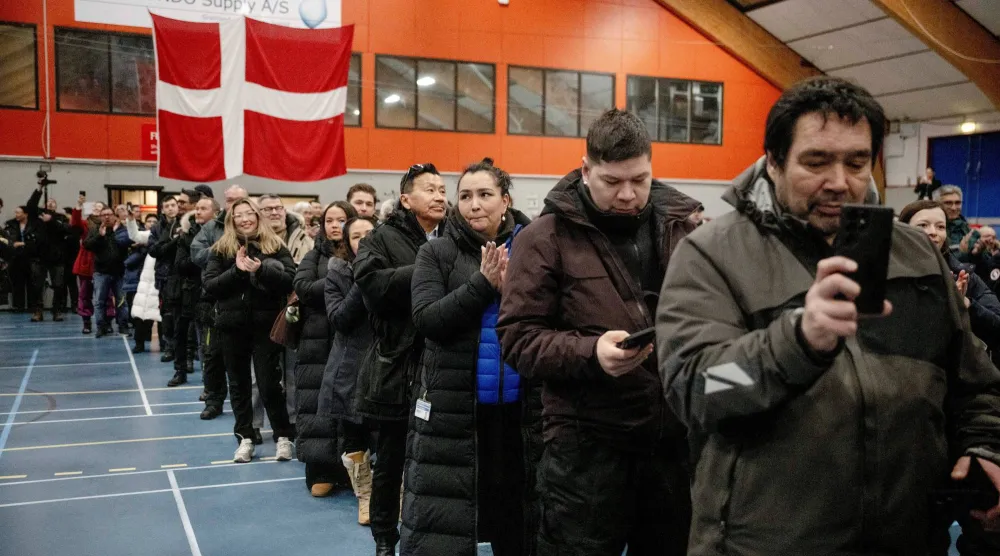 أشخاص يقفون داخل مركز اقتراع في نوك بغرينلاند (رويترز)