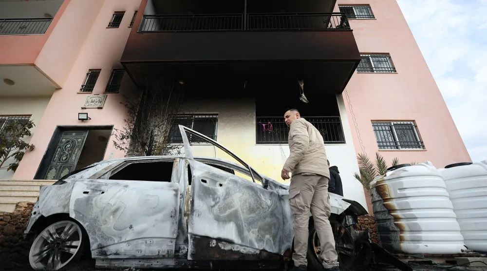 فلسطينيون يتفقدون الأضرار في قرية دير الحطب بالضفة الغربية بعد هجوم مستوطنين (إ.ب.أ)