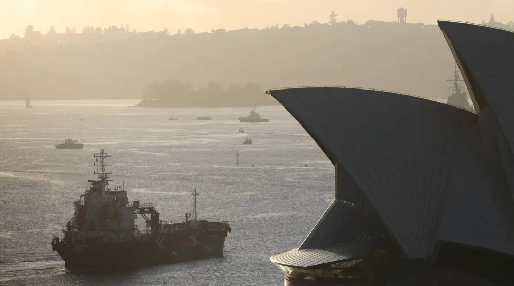 ناقلة منتجات نفطية تمر بجوار دار أوبرا سيدني مع شروق الشمس بأستراليا (رويترز)