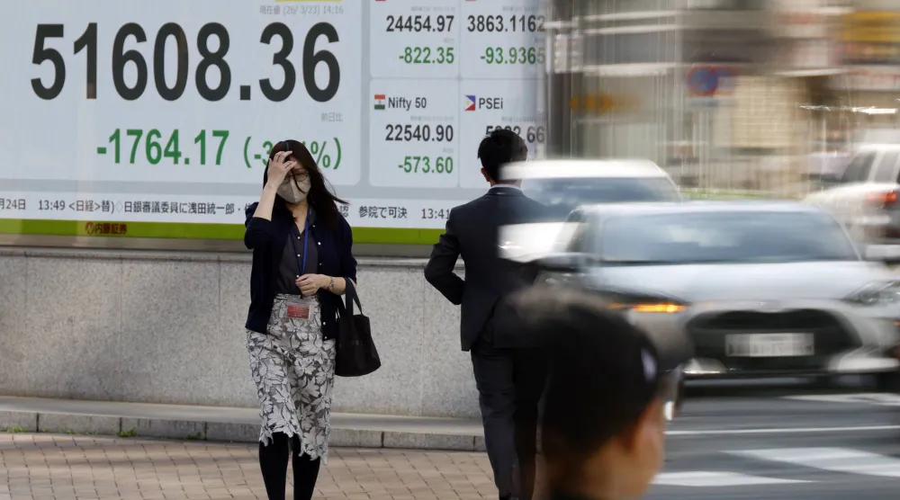 مشاة أمام شاشة تعرض حركة الأسهم في وسط العاصمة اليابانية طوكيو (إ.ب.أ)