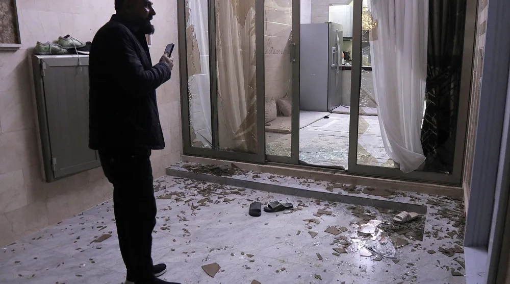 يتفقد السكان الأضرار التي لحقت بمبنى تحطمت نوافذه إثر اعتراض الدفاعات الجوية لصاروخ أو طائرة مسيّرة فوق حي سكني في أربيل (أرشيفية - أ.ف.ب)