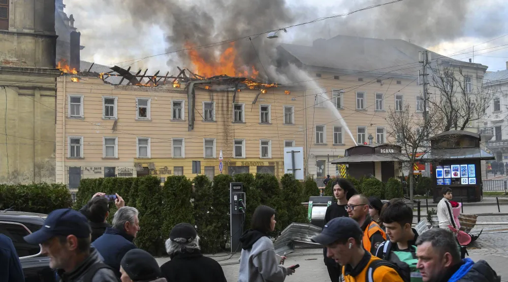 أوكرانيون يتجمعون أمام الكنيسة التاريخية بمدينة لفيف غرب أوكرانيا خلال عمليات إطفاء الحرائق بعد استهدافها بهجوم روسي يوم 24 مارس 2026 (إ.ب.أ)