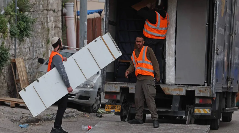 إسرائيليون يزيلون مقتنيات منزل فلسطيني خلال إخلاء 11 عائلة من منطقة بطن الهوى في حي سلوان بالقدس الشرقية (أ.ف.ب)