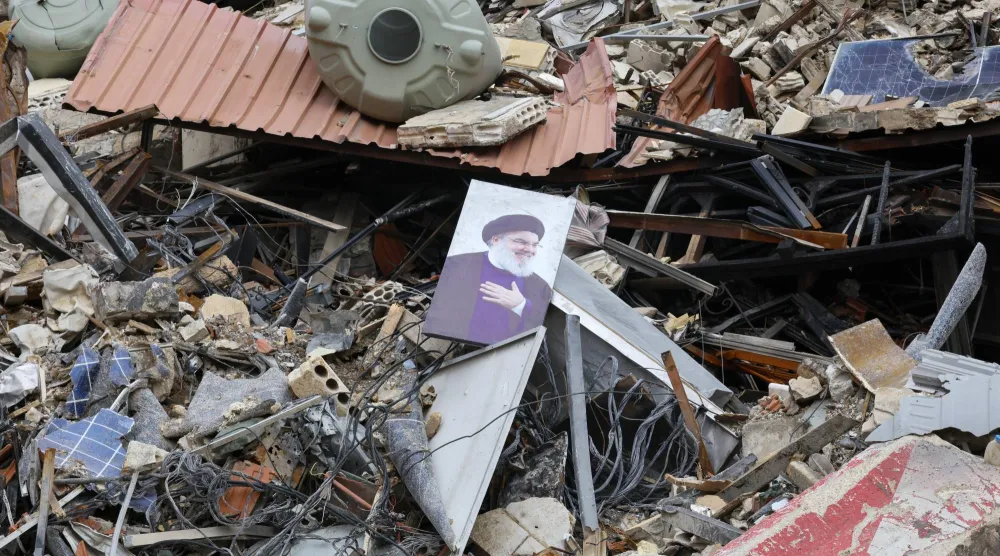 صورة للأمين العام الأسبق لـ«حزب الله» حسن نصر الله بين أنقاض مبنى لـ«القرض الحسن» دمرته غارة إسرائيلية في الضاحية الجنوبية لبيروت (إ.ب.أ)