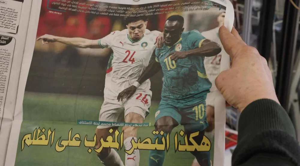 رجل يقرأ صحيفة مغربية بعد صدور قرار تجريد السنغال من اللقب الأفريقي (أ.ف.ب)