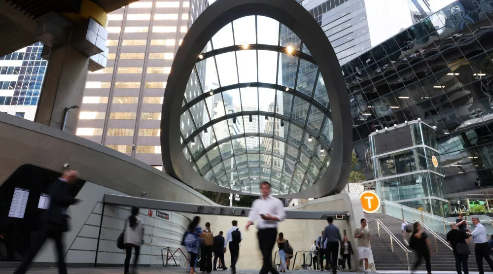 أشخاص يمرون أمام محطة قطار في سيدني بأستراليا (رويترز)