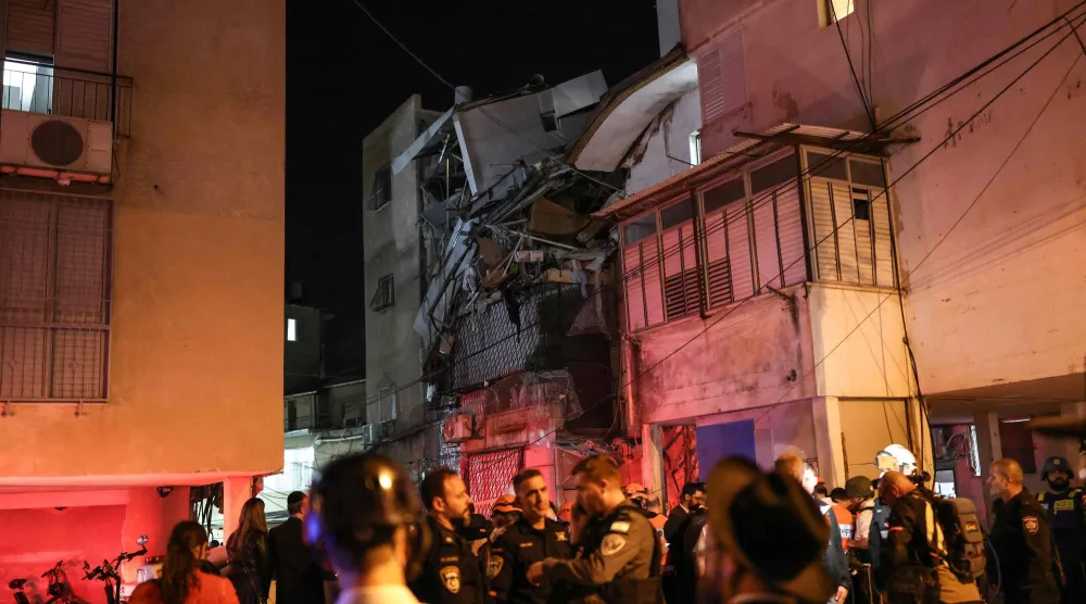 قوات أمن وفرق إنقاذ أمام مبنى متضرر بقذيفة في بني براك على الأطراف الشرقية لتل أبيب أمس (أ.ف.ب)
