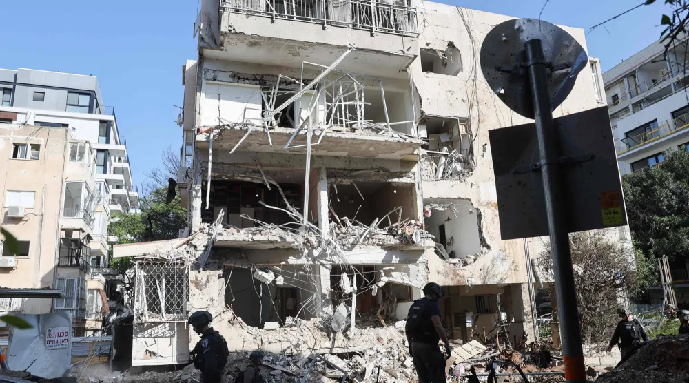 أفراد من فرق الإنقاذ الإسرائيلية في موقع الهجوم الصاروخي الإيراني في تل أبيب (أ.ف.ب)