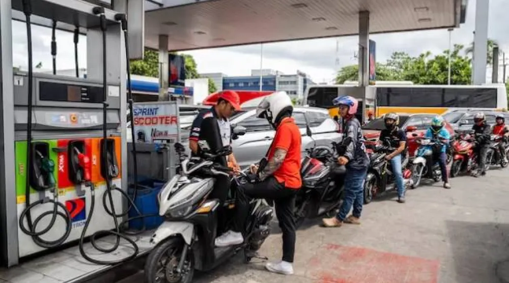 عامل يملأ دراجة نارية بالوقود في محطة بكويزون سيتي الفلبين (رويترز)