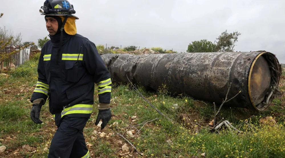 ضابط فلسطيني خلال تفقده بقايا صاروخ إيراني سقط في قرية بيتين شمال شرق رام الله أمس (أ.ف.ب)