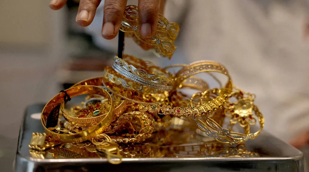 صائغ يزن حُلياً ذهبية داخل صالة عرض في أحمد آباد بالهند (رويترز)