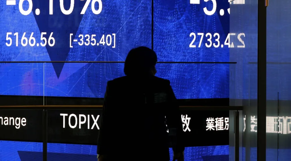 رجل يمر أمام شاشة تعرض حركة الأسهم في العاصمة اليابانية طوكيو (إ.ب.أ)