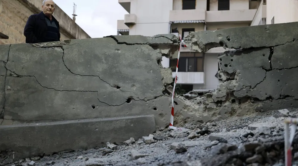 رجل يقف بجوار الموقع الذي سقطت فيه شظايا صاروخ تم اعتراضه بمنطقة حارة صخر بقضاء كسروان شمال بيروت 24 مارس 2026 (إ.ب.أ)