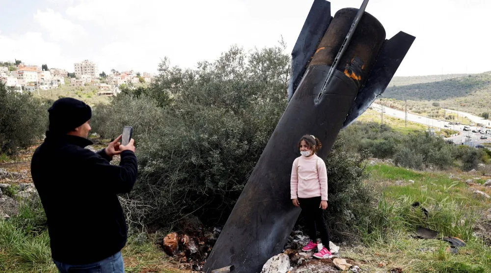 فتاة تقف لالتقاط صورة بجانب بقايا صاروخ عُثر عليه بالقرب من نابلس في الضفة الغربية (رويترز)