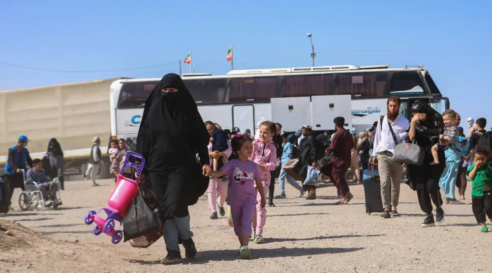 حافلة إيرانية تُنزل لاجئين أفغاناً عند نقطة الصفر على حدود إسلام قلعة بولاية هرات 24 يوليو 2025 (أ.ف.ب)