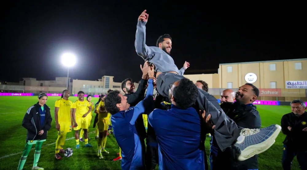 العلوني محتفلاً مع الجهاز الفني باللقب (نادي النصر)