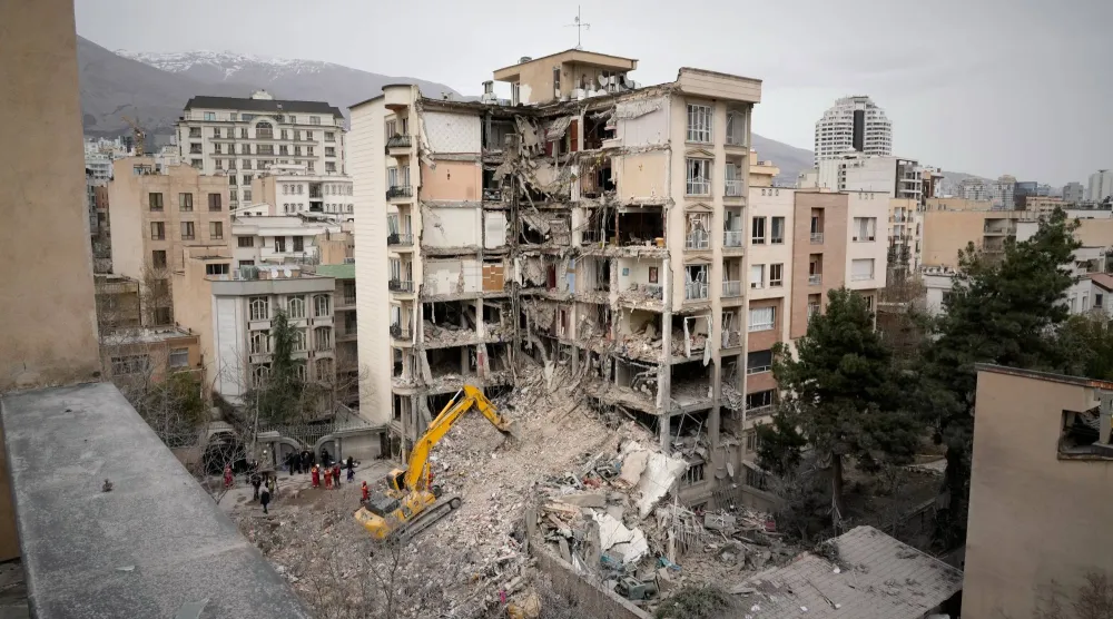 Iranian Red Crescent emergency workers use a bulldozer to clear rubble from a residential building that was hit in an earlier U.S.-Israeli strike in Tehran, Iran, Monday, March 23, 2026. (AP Photo/Vahid Salemi)