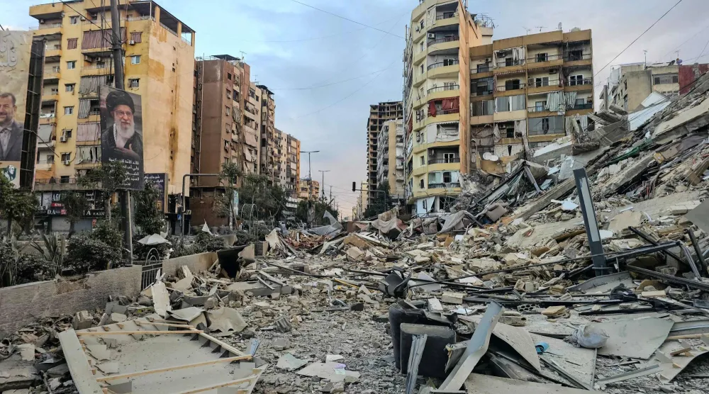 تظهر صورة فوتوغرافية بورتريه للمرشد الإيراني الراحل علي خامنئي إلى جانب أنقاض مبنى مدمر في موقع غارة جوية إسرائيلية ليلية على الضاحية الجنوبية لبيروت (أ.ف.ب)