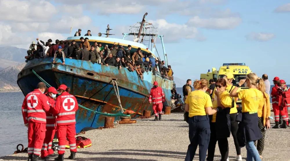 Kızılhaç gönüllüleri ve kurtarma ekipleri, Girit adası açıklarında gerçekleştirilen bir kurtarma operasyonunun ardından Paleochora limanında göçmenleri taşıyan bir balıkçı teknesinin yanında duruyor (Reuters)