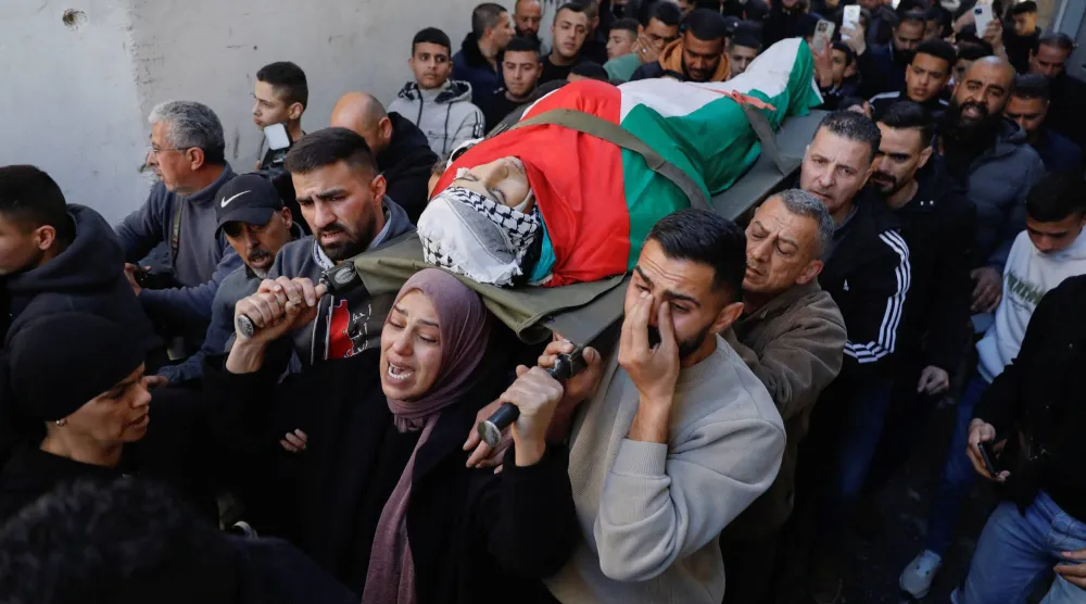 والدة الفتى الفلسطيني أدهم سيد صالح دهمان تقود جنازته في بيت لحم بالضفة الغربية المحتلة (رويترز)