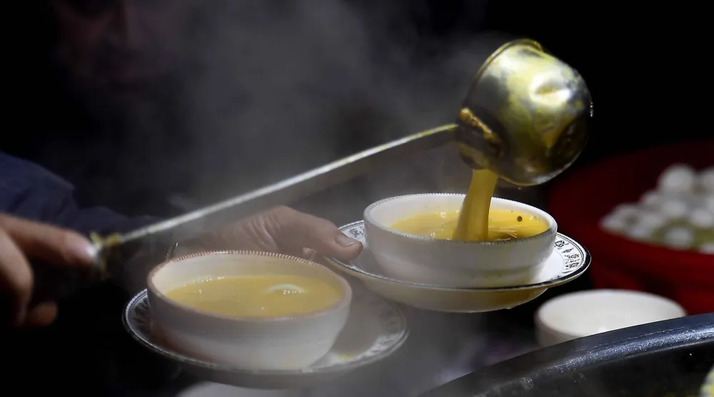 أشخاص يتناولون حساء الدجاج بمتجر على جانب الطريق في باكستان (إ.ب.أ)