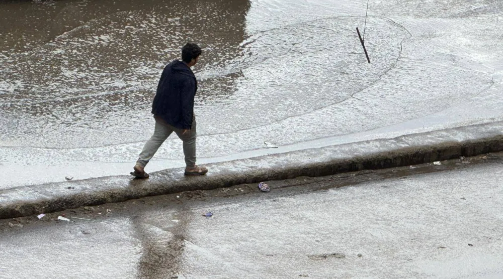 شاب مصري يسير وسط المياه في منطقة فيصل بمحافظة الجيزة بعد أن غمرت الأمطار الطرق (الشرق الأوسط) 