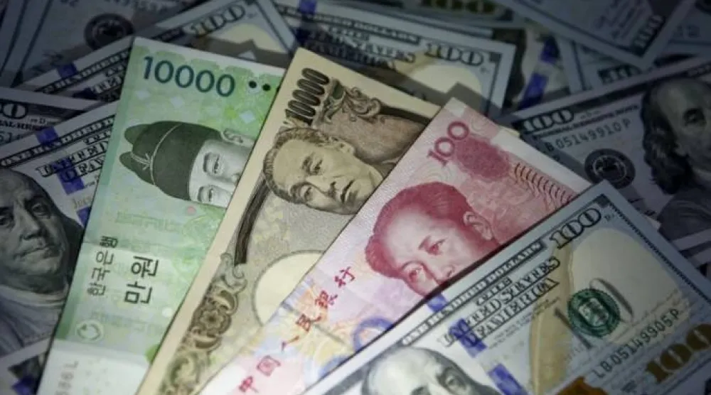 أوراق نقدية من الوون الكوري الجنوبي واليوان الصيني والين الياباني فوق أوراق نقدية من فئة 100 دولار أميركي (رويترز)