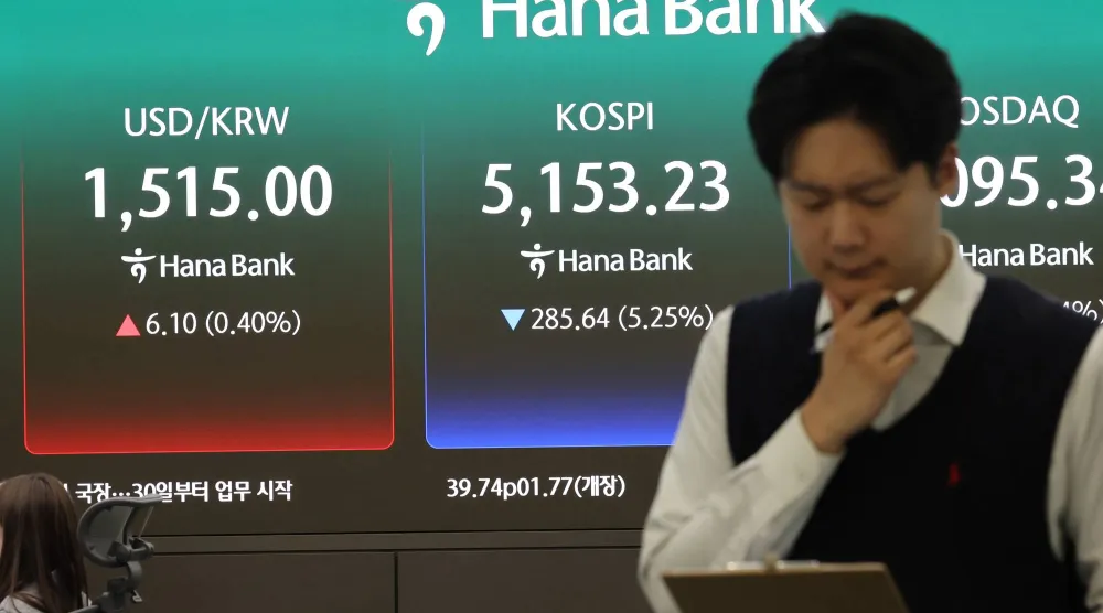 متداول يقف أمام شاشة تُظهر هبوط مؤشر كوسبي في سيول (إ.ب.أ)