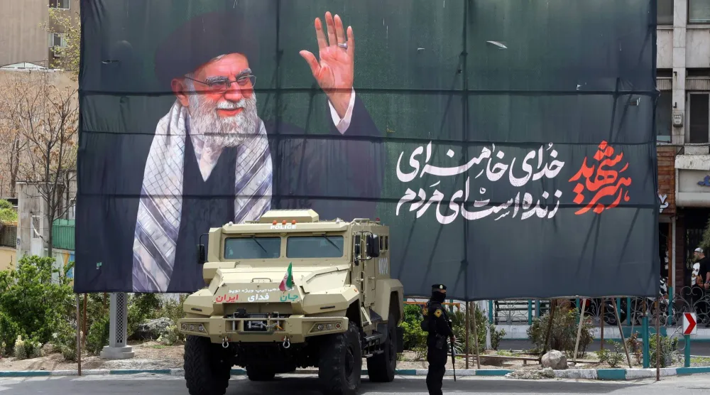 أحد أفراد قوات الأمن الإيرانية يقف حارساً بجوار لافتة للزعيم الإيراني السابق علي خامنئي في طهران - 30 مارس 2026 (إ.ب.أ)