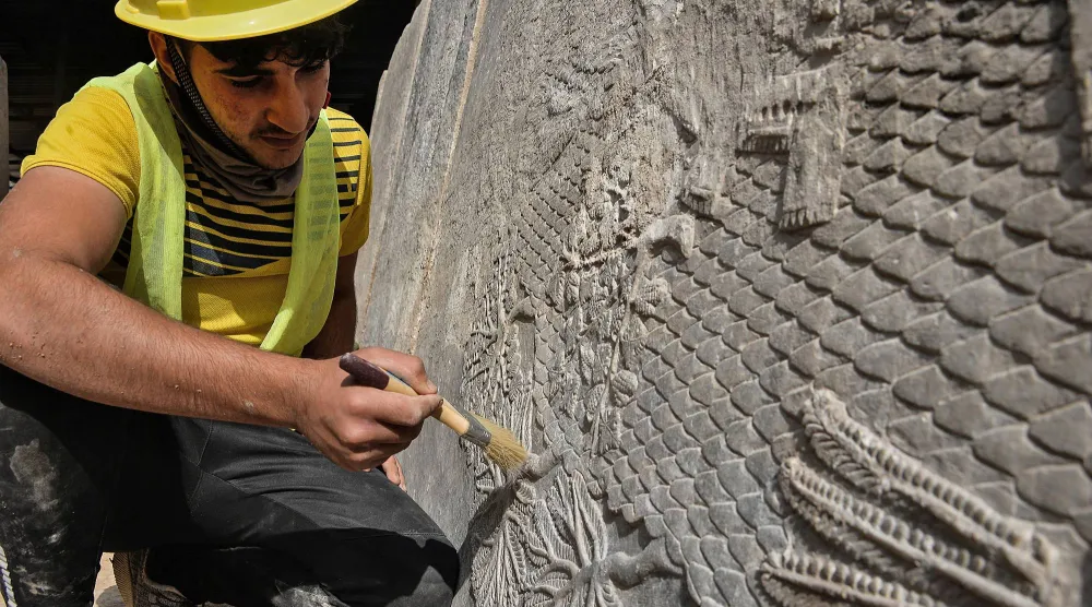 An Iraqi worker excavates a rock-carving relief recently found at the Mashki Gate, one of the monumental gates to the ancient Assyrian city of Nineveh, on the outskirts of what is today the northern Iraqi city of Mosul on October 19, 2022. (AFP)