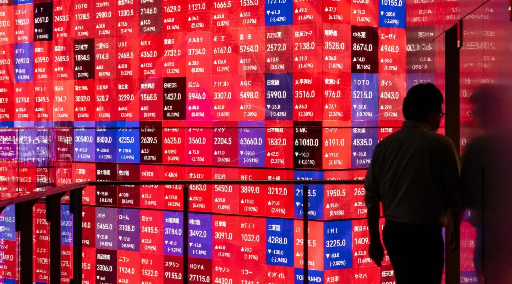 رجل يمرُّ أمام شاشة تعرض حركة الأسهم في العاصمة اليابانية طوكيو (أ.ف.ب)